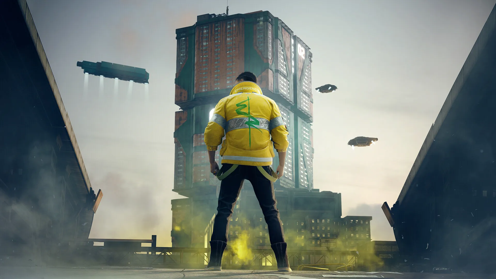 V, de espaldas y con una chaqueta amarilla, mira un edificio enorme de Night City con naves en el aire